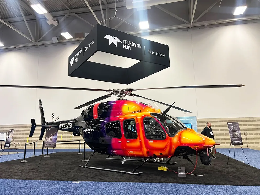 red and orange helicopter on display at verticon 2025.